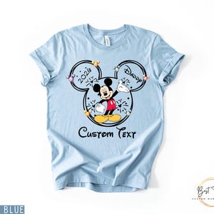 May include: Light blue t-shirt featuring a Mickey Mouse graphic with the text "2020 Daddy" inside a Mickey Mouse head outline. The shirt also includes the words "Custom Text" below the graphic.