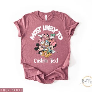 Puede incluir: Camiseta color malva jaspeado con un dise&ntilde;o de personajes de Disney, incluyendo Mickey y Minnie Mouse, Donald y Daisy Duck, Goofy y Pluto. El texto "MOST LIKELY TO" y "Custom Text" est&aacute;n impresos en la camiseta.