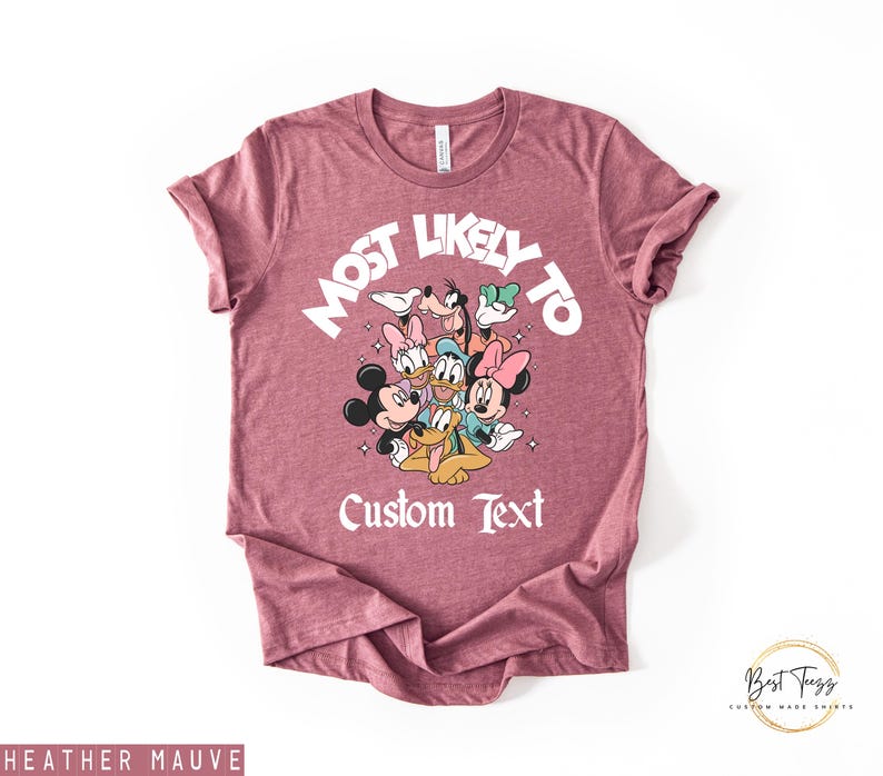 Puede incluir: Camiseta color malva jaspeado con un dise&ntilde;o de personajes de Disney, incluyendo Mickey y Minnie Mouse, Donald y Daisy Duck, Goofy y Pluto. El texto "MOST LIKELY TO" y "Custom Text" est&aacute;n impresos en la camiseta.