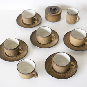 Può includere: Un servizio da tè in ceramica marrone con un motivo maculato. Il set comprende sei tazze, sei piattini, una zuccheriera con coperchio e una lattiera. Le tazze e i piattini hanno un design semplice e classico.