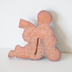 May include: Wooden figurine of an angel sitting with wings outstretched, painted in shades of brown and blue.