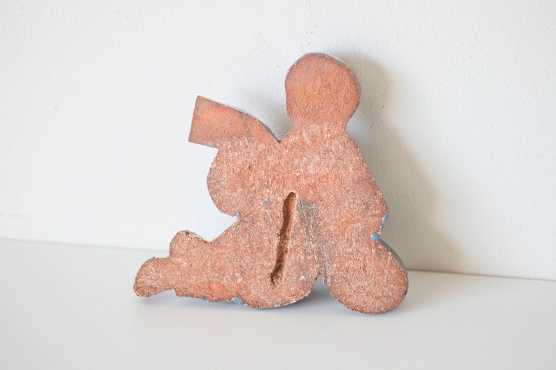 May include: Wooden figurine of an angel sitting with wings outstretched, painted in shades of brown and blue.