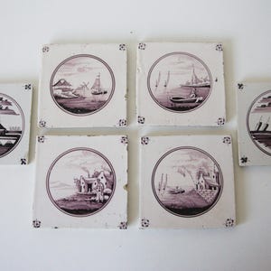 Può includere: Una collezione di sei piastrelle quadrate in ceramica con scene di paesaggi color seppia. Ogni piastrella presenta un design circolare con immagini di barche, edifici e acqua. Le piastrelle sono disposte su una superficie bianca.