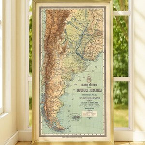 May include: A framed physical map of the Republic of Argentina, featuring topographical details in shades of brown, green, and blue. The text reads MAPA FÍSICO DE LA REPÚBLICA ARGENTINA, CONSTRUIDO POR EL DR. JOSÉ CHAVANNE, ESCALA 1:2.500.000, BUENOS AIRES 1900.