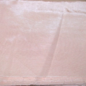 May include: A pale pink fabric with a subtle ribbed texture. The fabric is smooth and has a slight sheen.