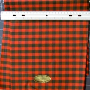 May include: Red and black plaid fabric with a small oval label that says "100% Cotton"