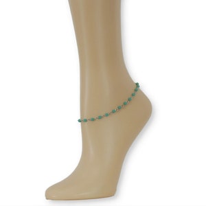 Op de afbeelding: Een zilveren enkelketting met turquoise blauwe kralen.