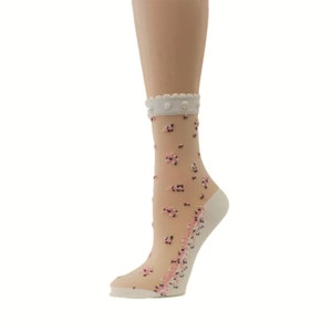 May include: White sheer socks with a floral pattern and a white lace trim at the top. The socks have small white pearl-like embellishments on the lace trim.