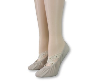 Puede incluir: Un par de calcetines invisibles beige con un delicado borde de encaje y pequeños detalles de perlas. Los calcetines están hechos de un tejido suave y elástico y están diseñados para ser usados con zapatos de corte bajo.