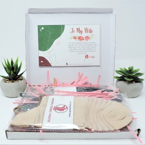 May include: A white gift box with pink tissue paper and a pair of socks. The box has a card inside that says "To My Wife" with a message of love and appreciation. The card is signed "Joseph".