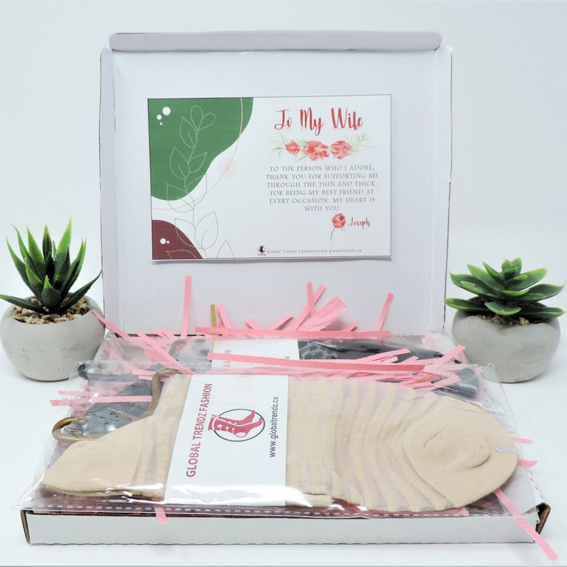 May include: A white gift box with pink tissue paper and a pair of socks. The box has a card inside that says "To My Wife" with a message of love and appreciation. The card is signed "Joseph".