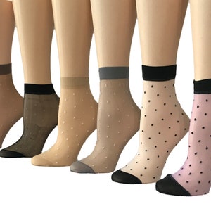May include: A collection of sheer ankle socks in various neutral colors, each featuring a contrasting black cuff and toe. The socks are adorned with small, evenly spaced polka dots, offering a delicate and stylish look.