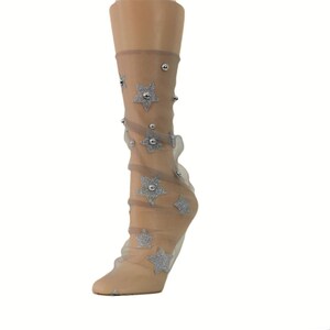 May include: A pair of sheer socks with silver glitter stars and silver beads. The socks are a light beige color.