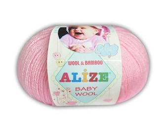 Può includere: Un gomitolo di lana rosa con un'etichetta che dice "Wool & Bamboo Alize Baby Wool". L'etichetta presenta anche un bambino dei cartoni animati.