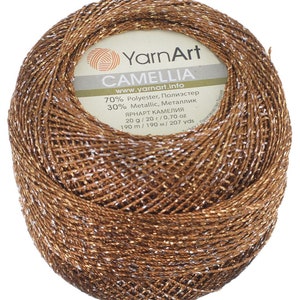 May include: A ball of brown yarn with silver metallic thread. The label reads "YarnArt Camelia" and includes information about the yarn's composition, weight, and yardage.