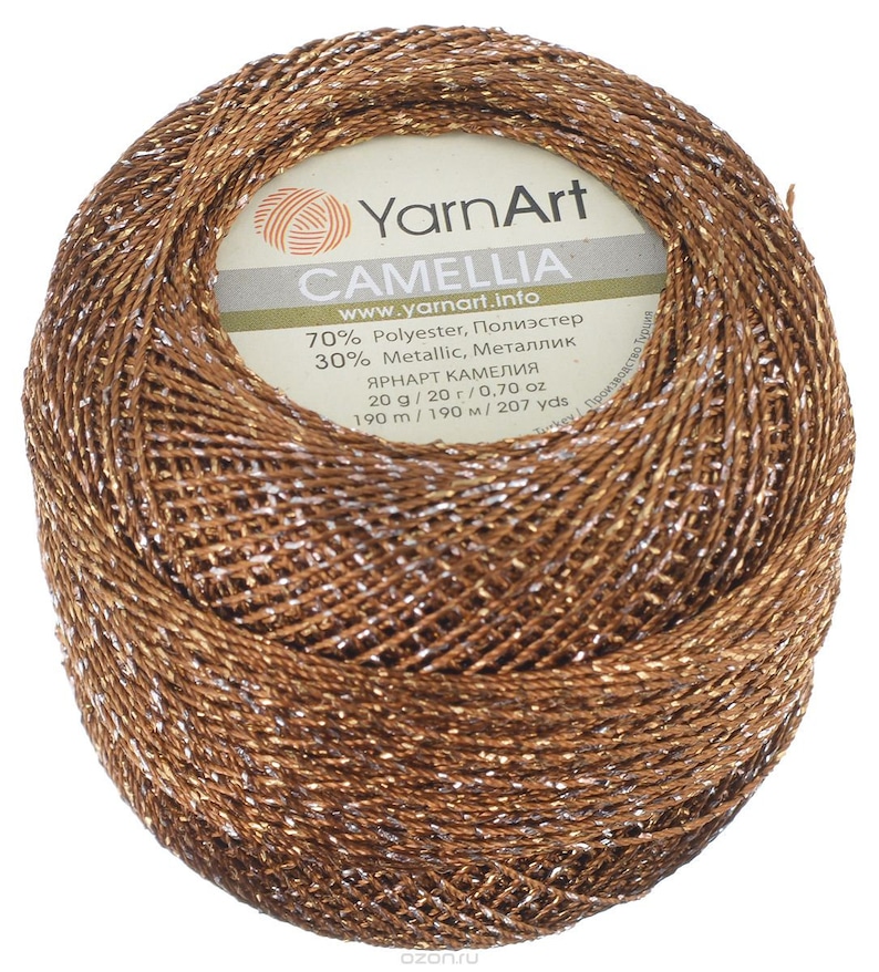 May include: A ball of brown yarn with silver metallic thread. The label reads "YarnArt Camelia" and includes information about the yarn's composition, weight, and yardage.