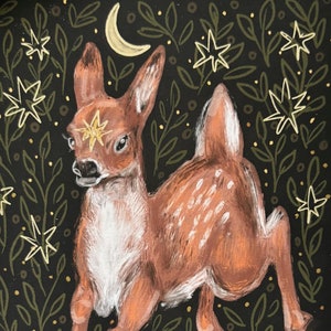 May include: A hand-painted illustration of a deer with a star on its forehead, surrounded by green leaves and yellow stars on a black background. The deer is looking to the left and has a crescent moon above it. The illustration is signed and numbered 2/50.