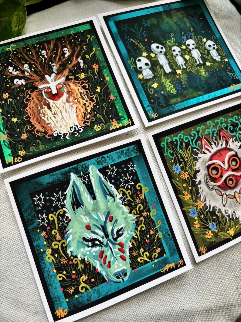 Puede incluir: Cuatro impresiones cuadradas con ilustraciones de personajes de la pel&iacute;cula animada 'La Princesa Mononoke'. Las impresiones est&aacute;n en papel blanco con bordes negros y detalles dorados. Los personajes incluyen un lobo, un esp&iacute;ritu del bosque y un esp&iacute;ritu enmascarado.