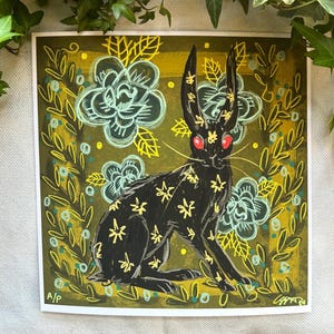 Pu&ograve; includere: Stampa artistica quadrata con un lepre nera con motivi floreali gialli e occhi rossi. La lepre &egrave; circondata da un bordo floreale con accenti verdi e gialli, su uno sfondo verde. L'opera d'arte ha uno stile illustrativo stravagante.