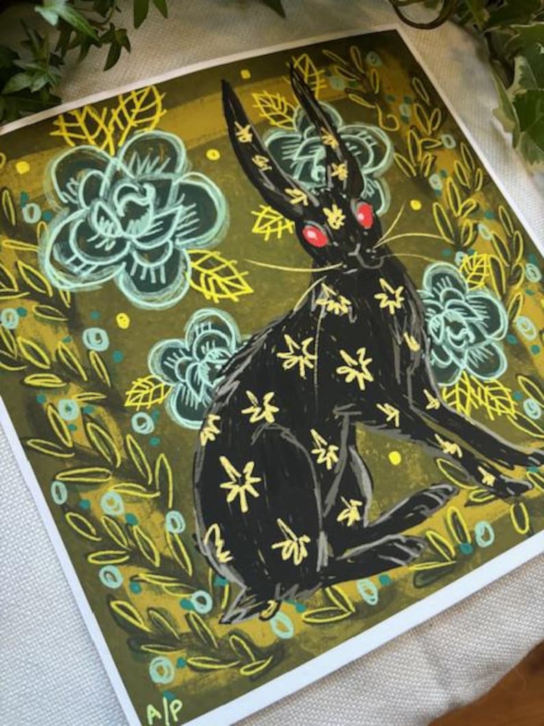 Pu&ograve; includere: Stampa artistica quadrata con un coniglio nero con motivi floreali gialli e occhi rossi. Il coniglio &egrave; ambientato su uno sfondo di fiori turchesi e fogliame verde oliva. L'opera d'arte ha uno stile illustrativo stravagante.