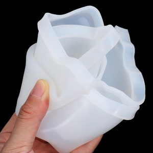 May include: A white silicone mold for making a cake or other dessert. The mold is flexible and has a wavy edge.