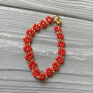 May include: A red and gold beaded bracelet with a gold clasp.