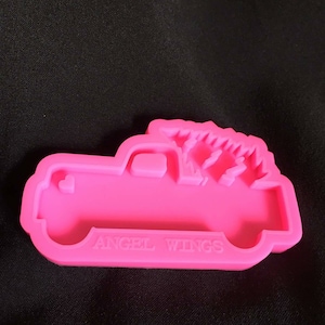 May include: Pink silicone mold shaped like a pickup truck with a Christmas tree in the bed. The mold says "Angel Wings" on the bottom.