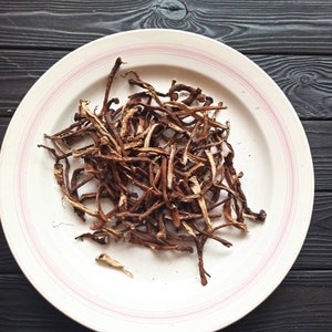 Könnte beinhalten: Ein weißer Teller mit rosa Rand enthält einen Haufen getrockneter brauner Wurzeln.