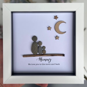 May include: A framed pebble art piece with a family of four, a moon and stars, and the text "Mummy We love you to the moon and back".