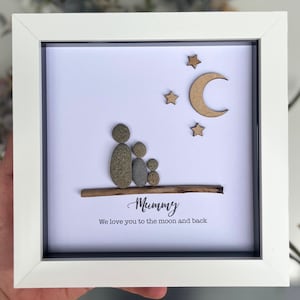 May include: A framed pebble art picture with a family of three, a moon and stars, and the text "Mummy We love you to the moon and back".