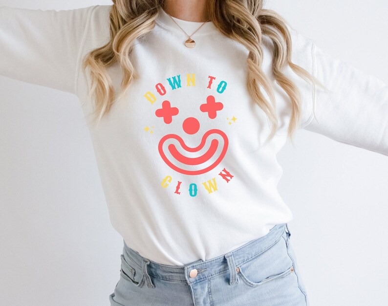 May include: White sweatshirt with a colorful graphic of a clown face and the text "Down to Clown".