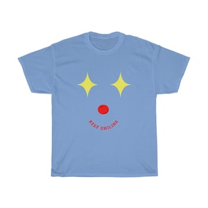 Puede incluir: Camiseta azul claro con un dise&ntilde;o de estrellas amarillas y una nariz roja, con el texto "KEEP SMILING" debajo.