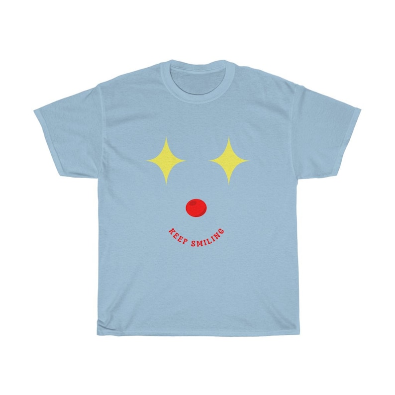 Puede incluir: Camiseta azul claro con un dise&ntilde;o de estrellas amarillas y el texto "Keep Smiling" en rojo.