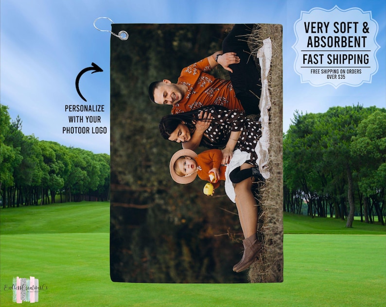 May include: A personalized golf towel featuring a family of three sitting on a blanket in a forest setting. The towel is white with a green border and has the text "PERSONALIZE WITH YOUR PHOTOOR LOGO" on the left side.
