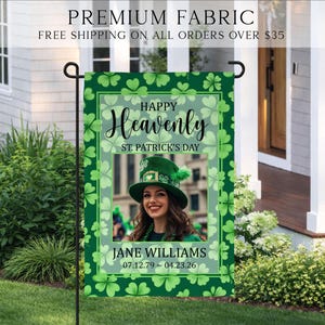 May include: A rectangular garden flag featuring a green shamrock pattern background. The text reads Happy Heavenly ST. PATRICK'S DAY, JANE WILLIAMS, and 07.12.79 - 04.23.26. A central rectangular frame displays a photograph of a person wearing a green hat.