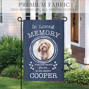 Puede incluir: Una bandera de jard&iacute;n rectangular con un fondo de grano de madera azul oscuro. Presenta el texto In Loving Memory, un marco circular que contiene la foto de un perro marr&oacute;n, el texto Your Paw Prints Forever In Our Hearts y el nombre Cooper.