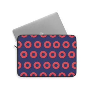 May include: A blue laptop sleeve with a repeating pattern of red donuts. The sleeve is closed and a silver laptop is partially visible inside.