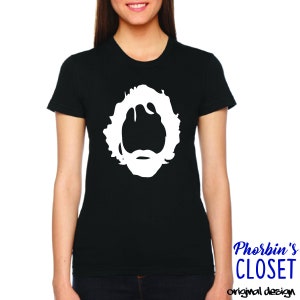 May include: Black t-shirt with a white silhouette of a person with long hair and a beard. The text "Phorbin's Closet original design" is printed on the bottom right corner of the shirt.