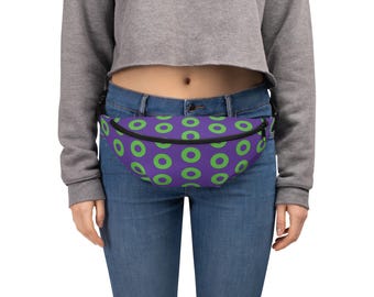 May include: A fanny pack featuring a repeating pattern of bright lime green circles on a solid purple background. The waist bag has a black zipper closure along the top edge and an adjustable black strap secured around the waist.