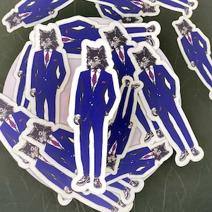 May include: A pile of stickers featuring a wolf wearing a blue suit and a red tie. The wolf has a serious expression on its face. The stickers are on a white background.