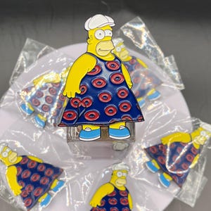 May include: A set of five yellow cartoon character pins wearing a blue dress with red donut patterns. The character has a white hat and a yellow face.