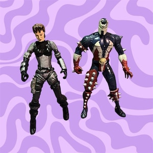 May include: Two action figures, one in black and silver armor and the other in red, white, and blue armor with a skull on the chest. Both figures have spiky armor and are posed in action stances.