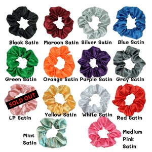 Puede incluir: Surtido de 14 scrunchies de sat&eacute;n de colores variados, incluyendo negro, granate, plateado, azul, verde, naranja, morado, gris, amarillo, blanco, rojo, rosa y menta. Los scrunchies est&aacute;n dispuestos en cuatro filas de tres, con el texto "SOLD OUT" sobre uno de los scrunchies.