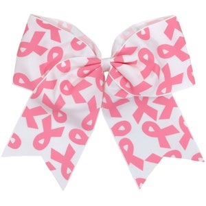 May include: A white cheer bow with a pink ribbon pattern. The ribbon pattern is a repeating design of pink ribbons.