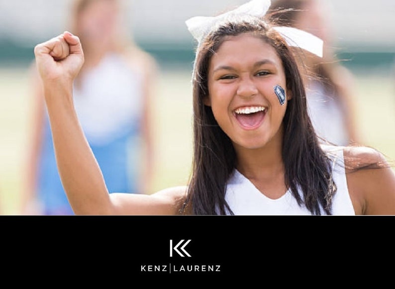 May include: A smiling person with dark hair and a white bow in their hair, wearing a white top, raises a fist in the air. A small face tattoo is visible. The logo "KENZ | LAURENZ" is at the bottom.