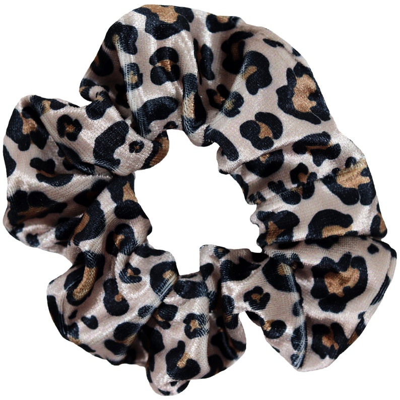 May include: A pink velvet scrunchie with a leopard print pattern in black and brown.