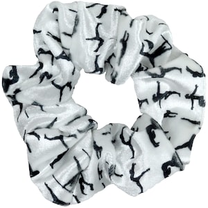 May include: White velvet scrunchie with a black silhouette pattern of people doing yoga poses.