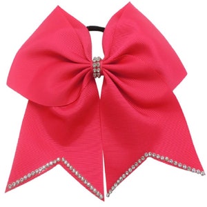 May include: A bright pink cheer bow with a rhinestone center and a rhinestone trim around the edges.