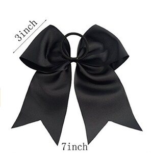 May include: A large black hair bow with a 7 inch width and 3 inch height. The bow is attached to a black elastic hair tie.