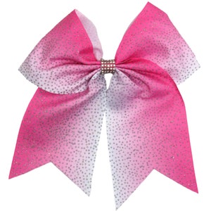 May include: A large pink and white ombre cheer bow with silver glitter. The bow has a rhinestone center.